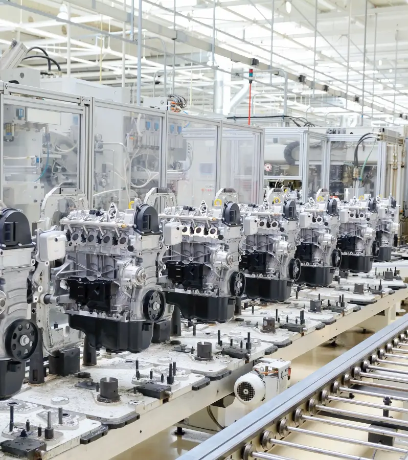 Row of automobile engines lined up on an assembly line conveyor inside a modern manufacturing plant