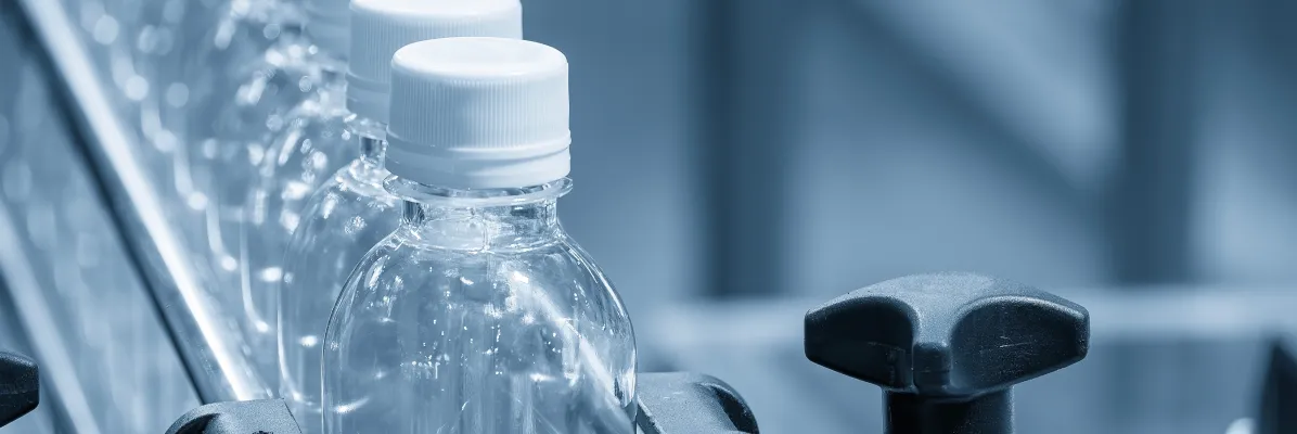 Sealed plastic water bottles moving along a sanitary beverage manufacturing conveyor line.