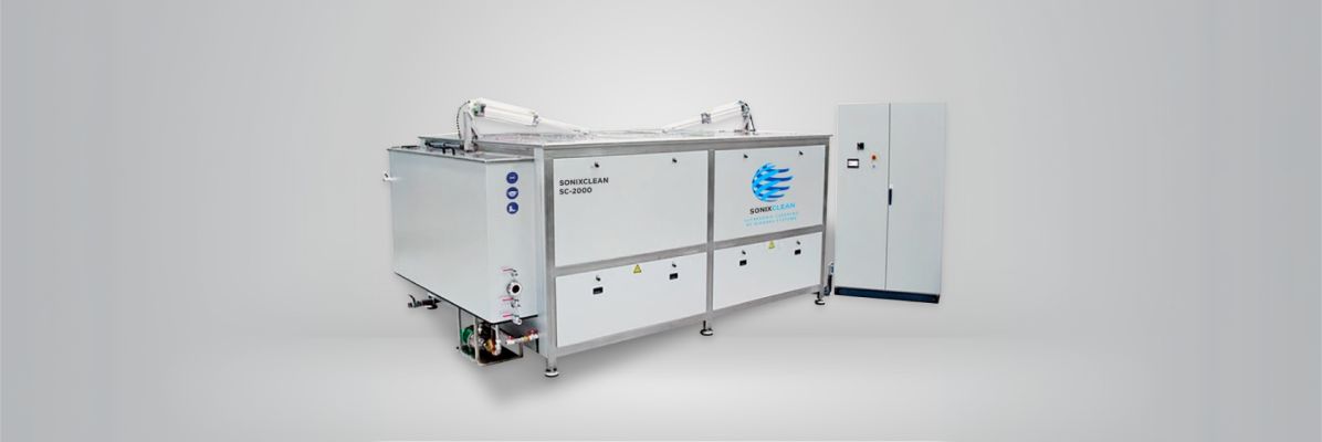 Large industrial ultrasonic cleaning system with control panel for manufacturing use.