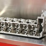 Engine cylinder head being cleaned in a large industrial ultrasonic cleaning tank.