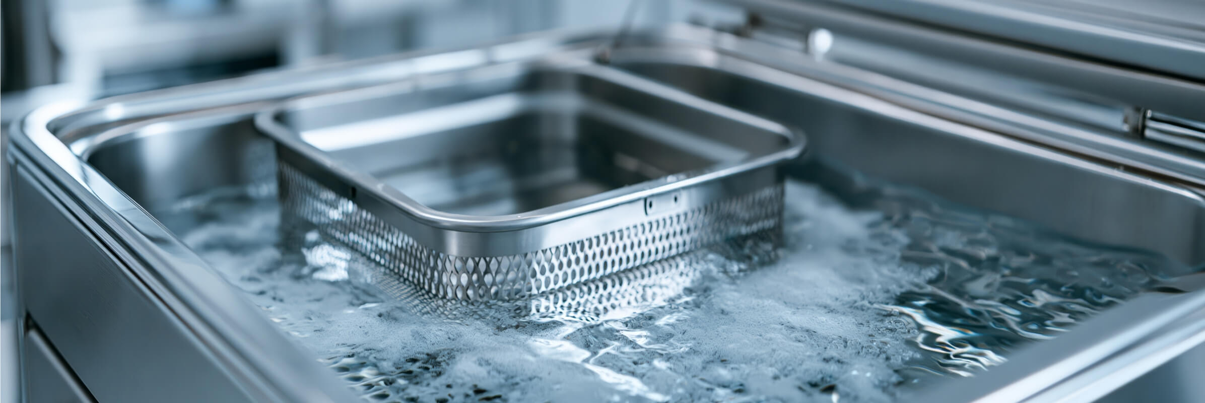 Perforated metal basket submerged in an ultrasonic cleaning tank.